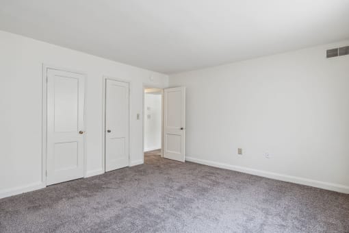 a bedroom with white walls and carpet and two doors