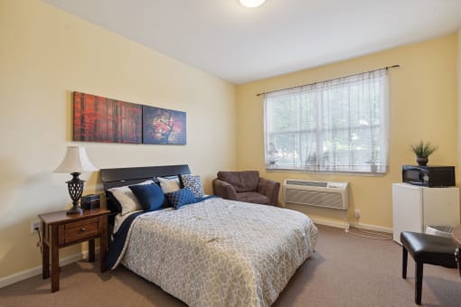 a bedroom with a bed and a chair in front of a window