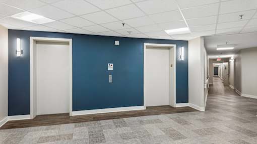 A long hallway with doors on both sides and a tiled floor.