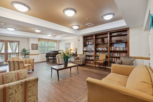 a room with couches chairs and a table with a vase of flowers and a piano