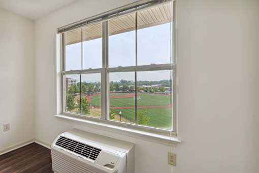 A room with a window overlooking a baseball field.
