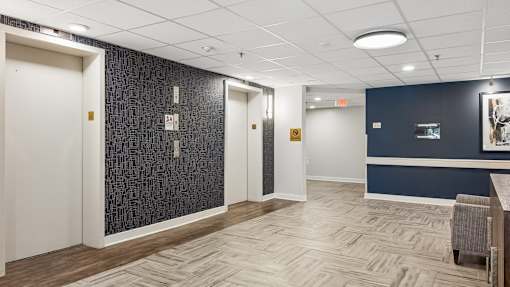 A hallway with a white door, a blue wall, and a wooden floor.
