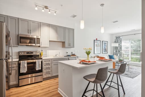 Model kitchen with stainless steel appliances and an island with stools at Legacy at Twin Rivers