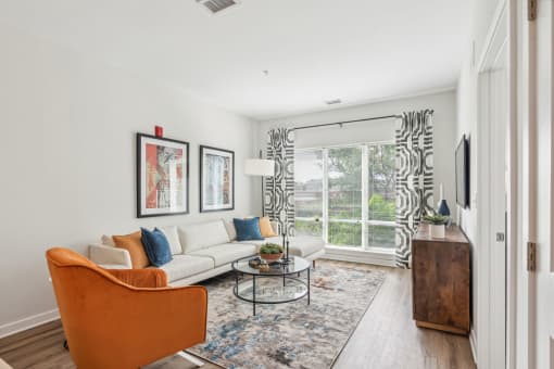 Living room with a white couch and a large window at Legacy at Twin Rivers