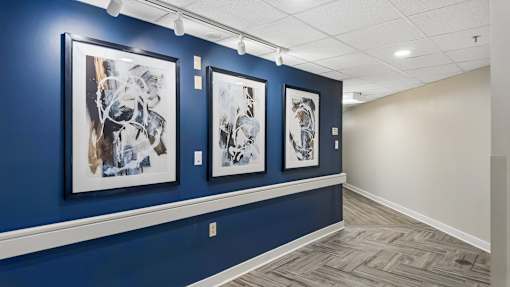 Three framed artworks hang on a wall.