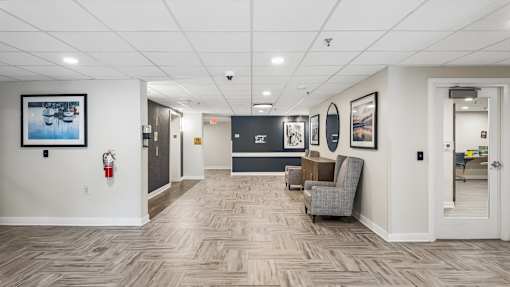 A hallway with a grey carpet and a wooden floor.