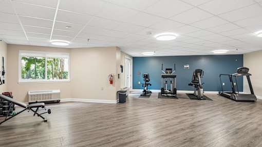 A gym with a variety of equipment including treadmills, exercise bikes, and weights.