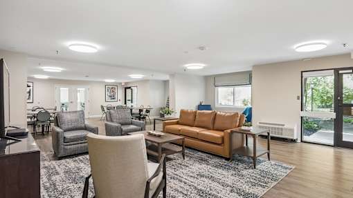 A living room with a grey couch, a brown couch, and a grey chair.