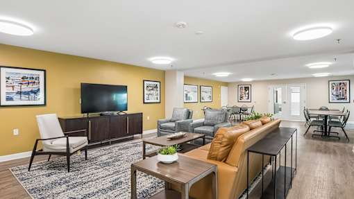 A living room with a television, couches, and chairs.