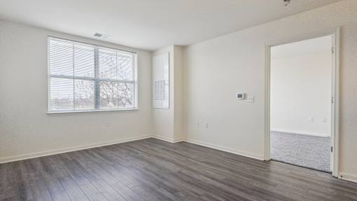 A room with a large window and a door leading to a balcony.