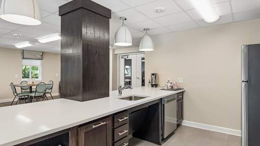 A kitchen with a white counter top and dark brown cabinets.