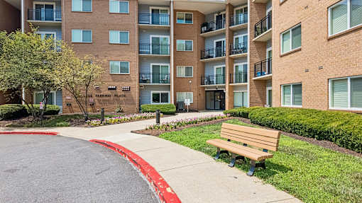 A brown bench is in front of a brick building.