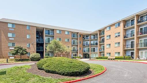A large apartment complex with a red curb and green bushes in the front.