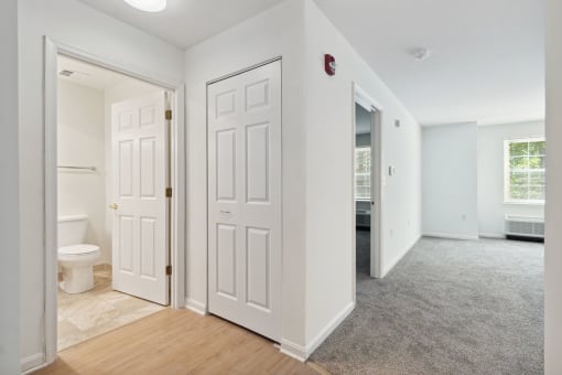 a bedroom with two doors and a bathroom in the background