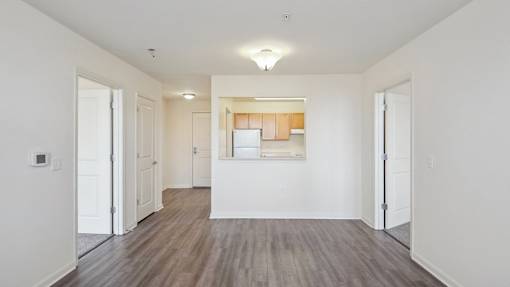 A room with white walls and wooden flooring with a window.
