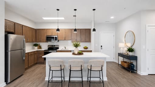 A modern kitchen with a white island and bar stools.