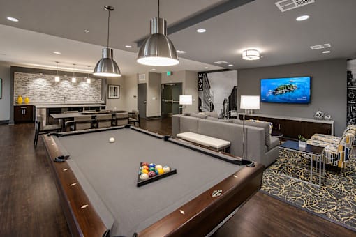 A billiard table is in the middle of a room with a TV on the wall.