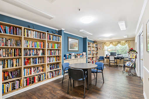 A room with a large bookshelf filled with books and a table with chairs.