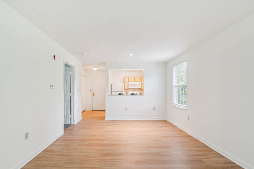 A white room with a wooden floor and a window.