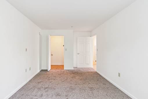 A room with a carpeted floor and two doors.