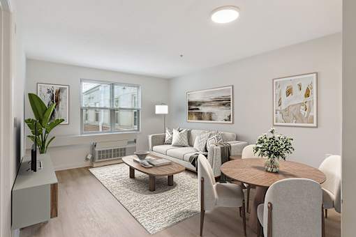 Bright living room in a Park Heights Place senior apartment with new flooring, large windows, and an open layout for easy mobility.