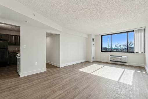 A spacious living room with a large window and a wooden floor.