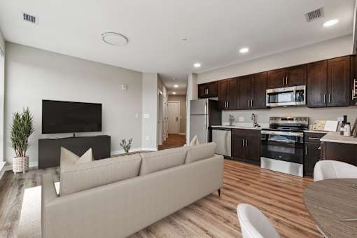 A modern living room with a couch, television, and kitchen area.