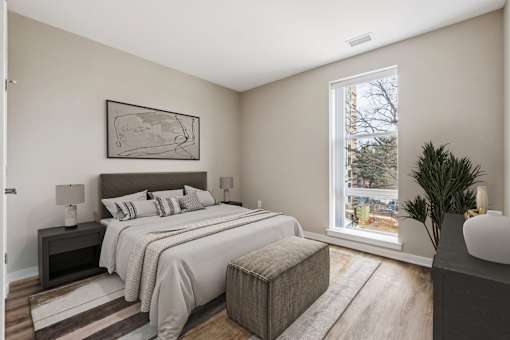 A bedroom with a large bed and a window overlooking a tree-lined street.