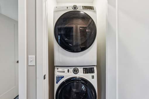 A white front loading washing machine with a black door is in a small room.