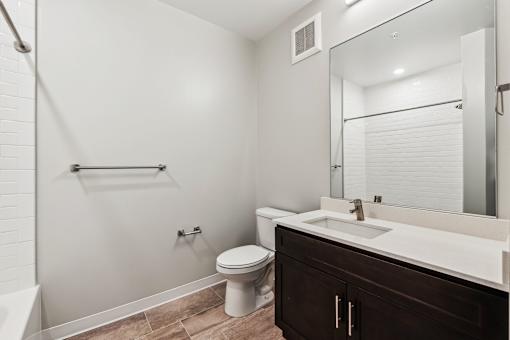 A white toilet sits in a bathroom next to a white sink.