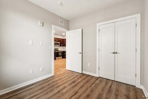 A room with white walls and wooden floors has two white doors.