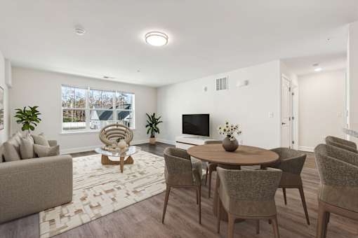 A living room with a brown sofa, a round table, and chairs.