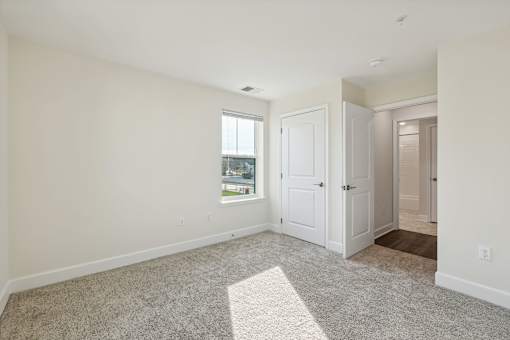 A room with a carpeted floor and a window.