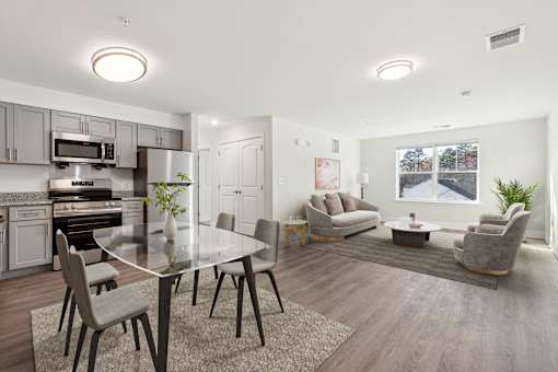 A modern kitchen with a glass table and grey chairs.