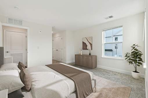A bedroom with a bed, nightstand, and a plant.