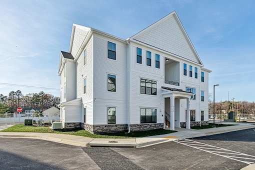 A white building with a parking lot in front.