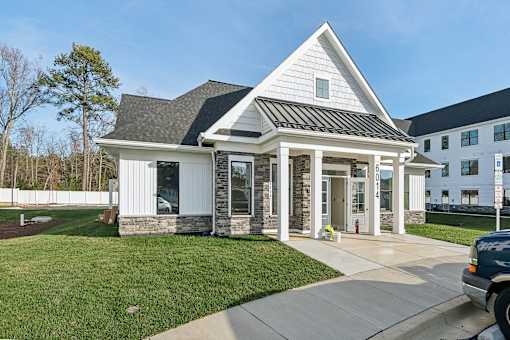 A white house with a black roof and a grey stone pillar.