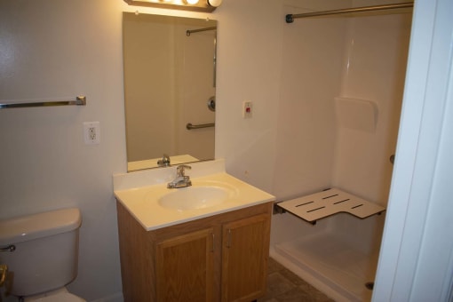 A well-lit bathroom with a sink, mirror, and bathtub.