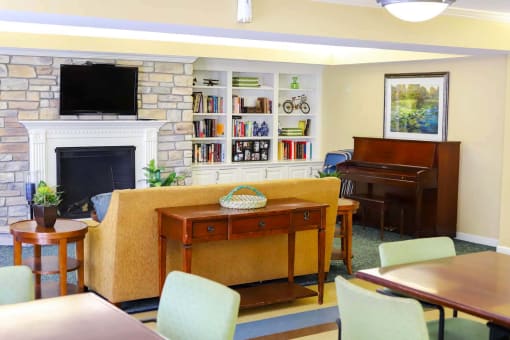 A community room with a fireplace, bookshelves, and a painting.