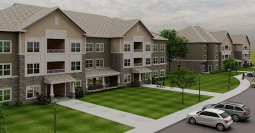 A large apartment complex with a grassy courtyard and parked cars.