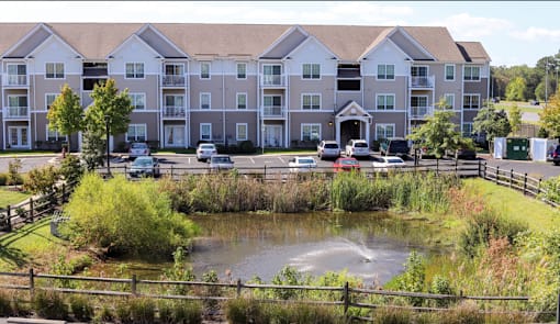 A large apartment complex with a pond in front.