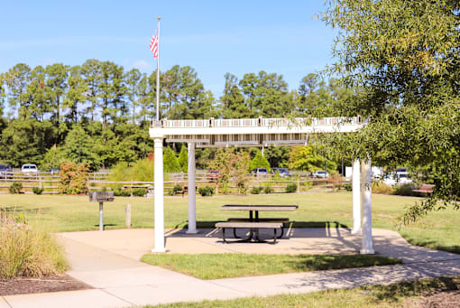 A flag pole with the American flag flying in front of a white archway.