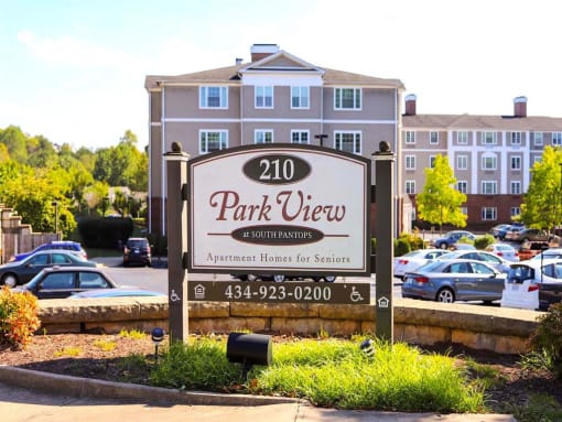 Exterior view of Park View at South Pantops, a senior apartment community in the Carriage Hill area near Charlottesville, featuring well-maintained buildings, landscaped grounds, and convenient on-site parking for adults age 62 and better.