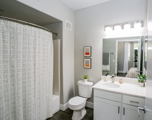 Octave Apartments  a bathroom with a white sink and toilet next to a shower with a curtain