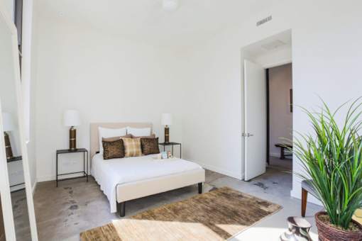 A bedroom with a large bed and a potted plant.
