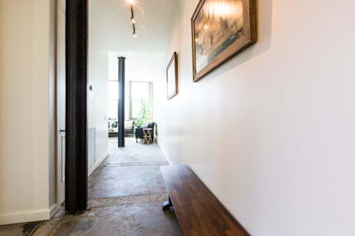 A hallway with a wooden bench and a painting on the wall.