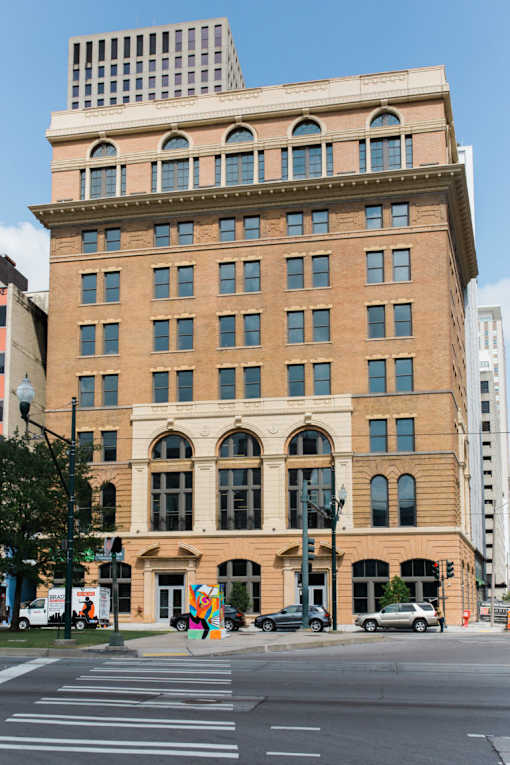 A large, old building with many windows sits on a city street corner.