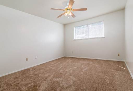 A room with a ceiling fan and carpeted floor.