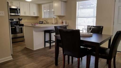 A kitchen with a table and chairs.