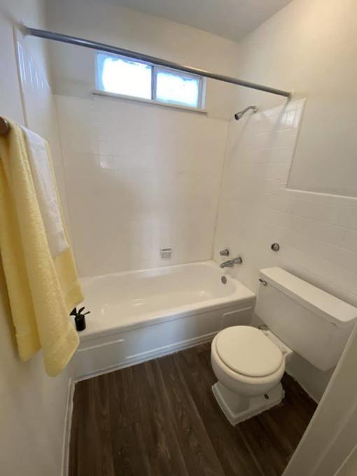 A small bathroom with a toilet, tub, and window.